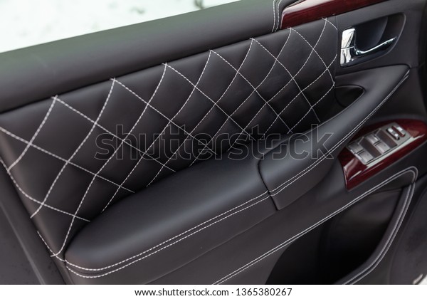 Interior of a\
luxury car with leather interior overtightened stitching in the\
form of a diamond of white thread at door trim in a vehicle repair\
shop. Design atelier auto\
service.