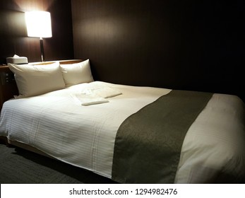 Interior Of The Luxury White Comfortable Double Bed With Two Pillows In A Low Light Bedroom In The Elegance Suite Hotel.