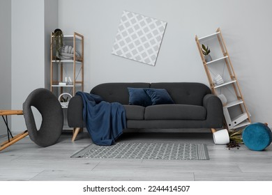 Interior of messy living room with shelf units and sofa near light wall