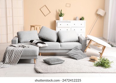 Interior of messy living room with sofa and pillows on carpet