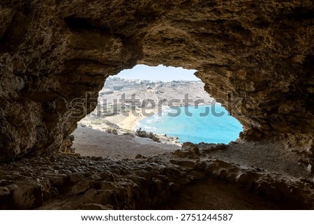 Interior of Mixta Cave framing Ramla Bay with turquoise sea and sandy beach on Gozo, Malta, seen through the cave opening.