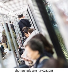 Interior of moder Tokyo metro with passengers on seats and businessman using hir cell phone by exit door. People commuting to work by public transport. Square composition. - Shutterstock ID 340283288
