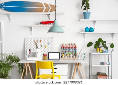 Interior of modern atelier with tailor's workplace, shelves and surfboard - Powered by Shutterstock