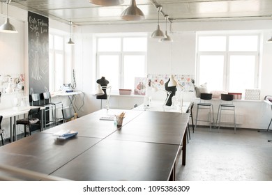 Interior Of Modern Atelier Workshop With Wooden Workstation In Foreground And Sewing Dummies, No People, Copy Space