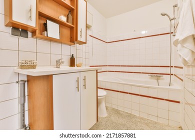 Interior of modern bathroom with bathtub and sink in wooden counter furnished with wooden shelf rack