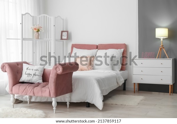 Interior of modern bedroom with stylish folding\
screen and sofa