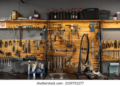 Interior Of Modern Bicycle Garage Or Workshop With Many Professionals Tools And Equipment. Bike Service, Repair And Upgrade. Broken Cycling Wheel On Desk Ready For Fixing, Installing Or Replacement