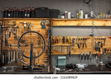 Interior Of Modern Bicycle Garage Or Workshop With Variety Professionals Tools And Equipment. Bike Service, Repair And Upgrade. Broken Cycling Wheel On Table For Fixing, Installing Or Replacement