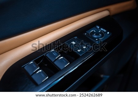 Interior of a modern car with leather inserts. Side door buttons: window lifters, mirror adjustment buttons, door lock. Inside the car.