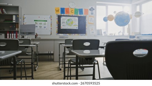 Interior of Modern Empty Elementary School Classroom with Desks for Students, Chalkboard, Hanging Solar System Models and Colorful Posters. Educational and Inspiring Learning Environment for Children.