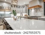 Interior modern farmhouse kitchen and dining room with white countertops bar stools large dining table stainless appliances and view to living room with vaulted ceiling