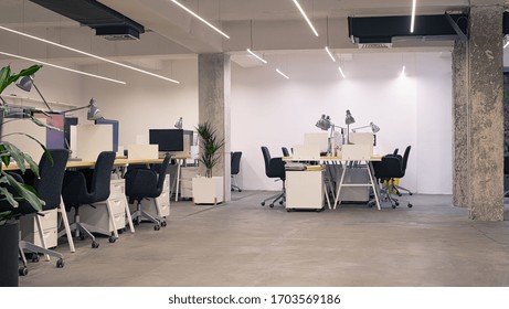 Interior Of Modern Industrial Office With Desks And Computers. Empty Open Space Office With Essential Amenities. Stylish Coworking Area With Furniture.