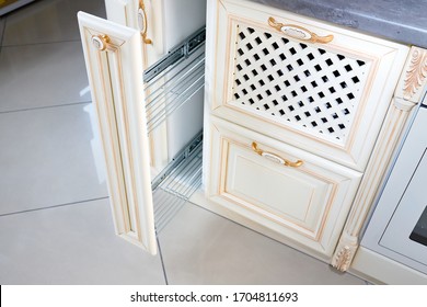 Interior Of Modern Kitchen In Classic Style With Golden Elements In Beige Colors. Pull Out Spice Rack Cabinet Filler Pantry. Vertical Drawer For Spices Shelf Under Countertop With Front Wooden Panel.