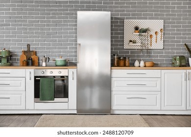 Interior of modern kitchen with counters and stylish fridge