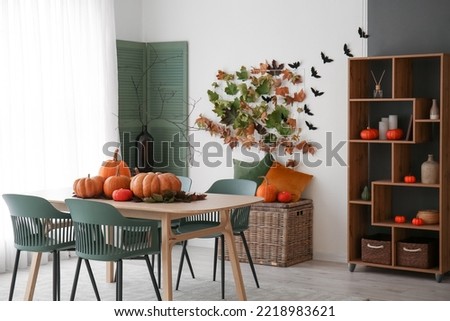 Interior of modern kitchen with fresh pumpkins, dining table and shelving unit