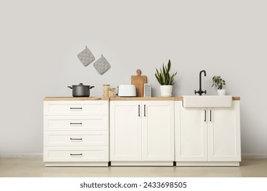 Interior of modern kitchen with utensils, sink and electric stove on white counters - Powered by Shutterstock