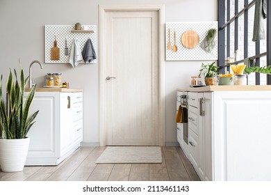 Interior of modern kitchen with white counters, door and peg boards