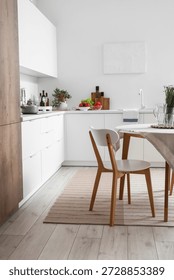 Interior of modern kitchen with white counters, dining table and stylish rug