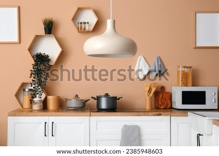 Interior of modern kitchen with white counters, electric stove and microwave oven