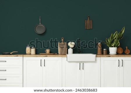 Interior of modern kitchen with white counters, utensils and sink