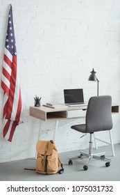 interior of modern living room with american flag on brick wall and table with laptop