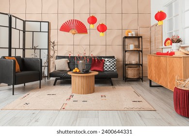 Interior of modern living room with black sofa, armchair and traditional Chinese decorations. Chinese New Year celebration