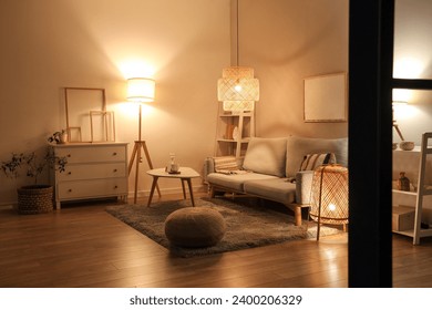 Interior of modern living room with grey sofa, coffee table and glowing lamps at evening