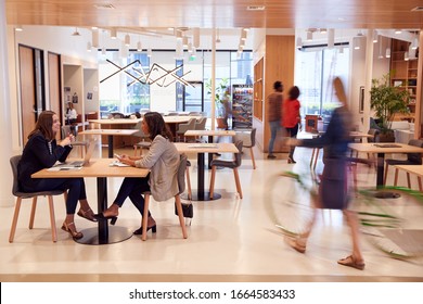 Interior Of Modern Open Plan Office With People Working And Commuters Arriving On Bikes