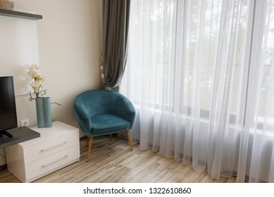 Interior of modern room with comfortable armchair near to large window with sheers and gray curtains - Shutterstock ID 1322610860
