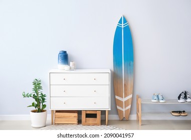 Interior of modern stylish hall with surfboard, shoe stand and chest of drawers - Powered by Shutterstock