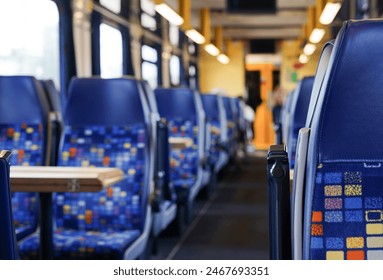 interior of a modern train or bus with rows of blue seats, and a central aisle, all unoccupied, public transportation - Powered by Shutterstock