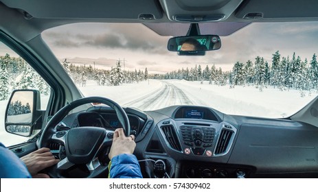 An Interior Of A Modern Van Car Driving Through A Snowy Forest Road In A Cloudy Cold Winter Day With Drivers Hands On A Steering Wheel And His Head Reflecting In A Rear Window