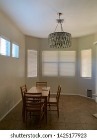 Interior Of New Home With Table And Chairs And Large Overhead Light Fixture With Bay Of Windows