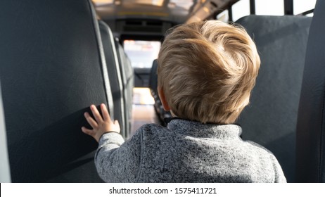 Interior Of A New School Bus With Lone Boy Looking Down The Aisle.