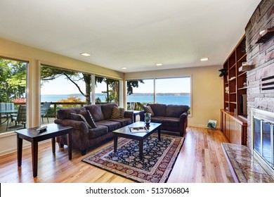 Interior Of Nicely Furnished Living Room With Large Windows Overlooking Back Deck. Has Hardwood Floor, Brown Chocolate Sofas, Persian Style Rug, Natural Stone Wall Trim And A Fireplace. Northwest, USA