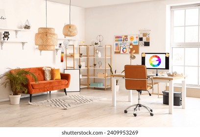 Interior of office with graphic designer's workplace, shelves and sofa
