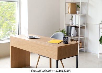 Interior Of Office With Modern Workplace, Shelving Unit And Houseplants