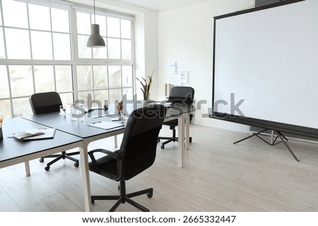 Interior of office with table and projector screen prepared for meeting