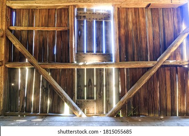 The interior of an old barn with sunlight streaming in through the boards.
