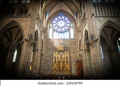 Interior of old catholic church with golden altar in centre, large stained-glass window over it, huge arches and high columns made of grey stone. Religion and faith. Holy places and architecture. - Powered by Shutterstock