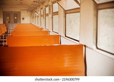 The Interior Of An Old Empty Retro Train Car With Orange Seats On A Bright Day. Blurred Background Inside The Train. Traveling Alone.