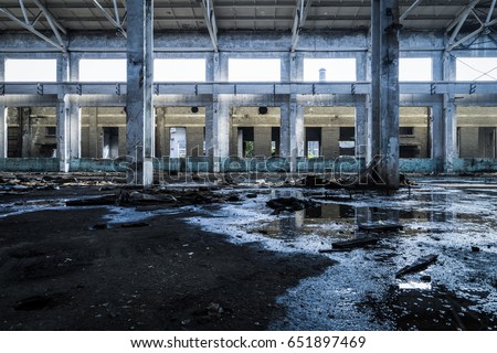 Interior of old factory buildings destroyed. Ruins of industrial enterprise, dark debris destroyed factory premises in factory as result of economic crisis and earthquake.