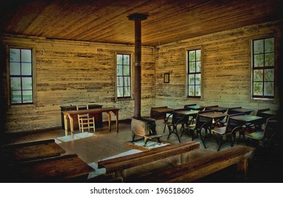 The interior of an old one room school house. It shows the old school desks and benches with a wood stove in middle of the room. This photo has had hdr applied as well as vignette and grunge texture. 