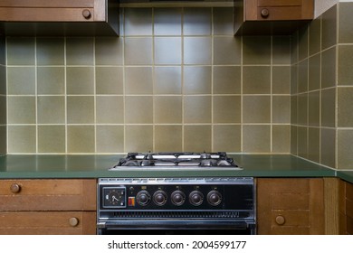 Interior Of A Old Retro Vintage Kitchen With Antique Oven With Brown Wooden Cabinets, Green Old School Stylish Tiles,needs Renovation Close To