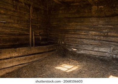 Interior the old rustic stable with sunlight. Inside the wooden barn with hay and straw on the floor. Wooden beam walls 