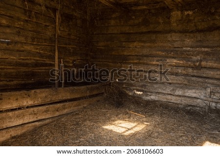 Interior the old rustic stable with sunlight. Inside the wooden barn with hay and straw on the floor. Wooden beam walls 