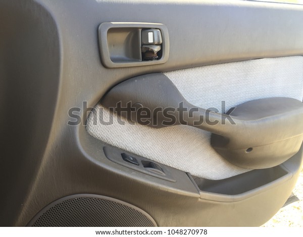 An interior open car door on\
a sunny day. Missing a door handle showing the interior\
design.