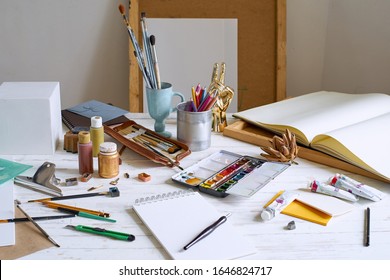 Interior of painting studio of freelance artist. Gypsum shapes, brushes, pencills, ink and paint bottles with sketchbooks on the table. Freelance artist lifestyle concept. Copy space - Powered by Shutterstock