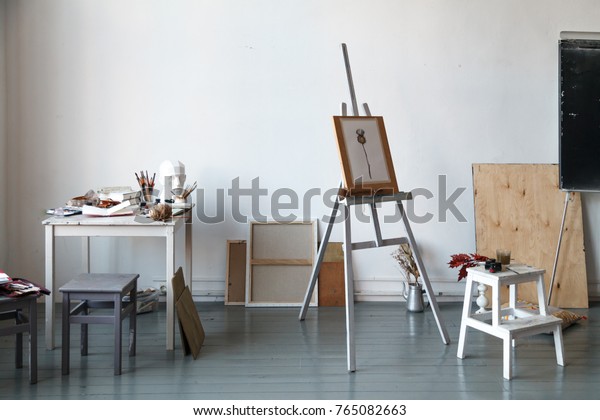 Interior of painting\
studio of freelance artist. Gypsum head, brushes, pencills, ink and\
paint bottles with sketchbooks on the table. Freelance artist\
lifestyle concept