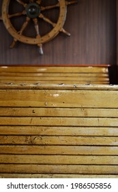 Interior Of The Passenger Compartment On The Boat, Wooden Seats And A Steering Wheel On The Wall